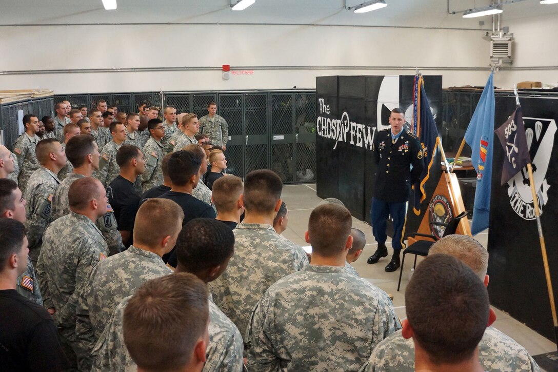 A man in uniform addresses a crowd of soldiers.