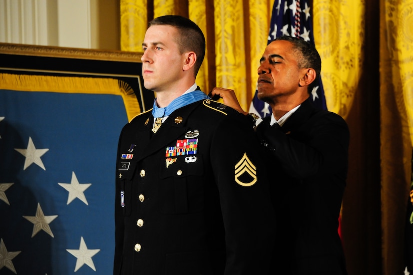 A man fastens a medal around a soldier’s neck.