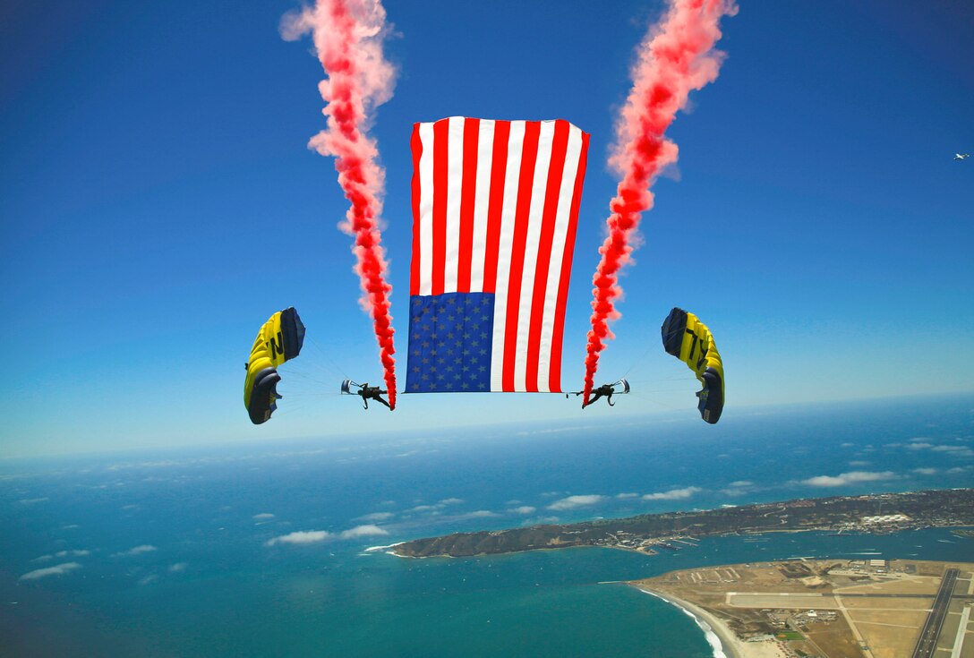 Two sailors conduct a tethered flag with smoke jump.