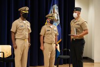 A Sailor at Naval Surface Warfare Center, Carderock Division holds the Legion of Merit Award that Capt. Michael Richman (center), chief of staff for Naval Surface and Undersea Warfare Centers, presented to Capt. Cedric McNeal for his successful time as commanding officer of Carderock Division.