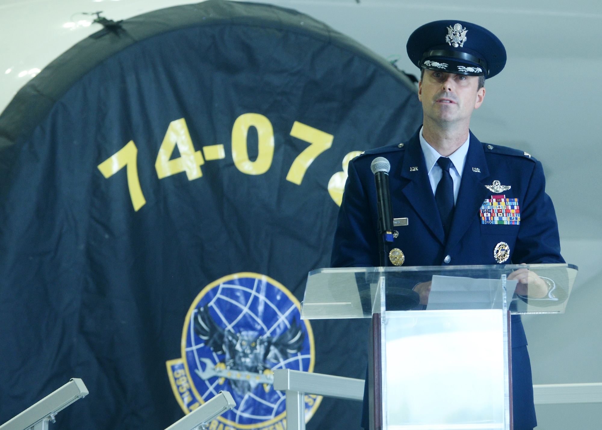 Airman stands at podium in front of E-4B aircraft