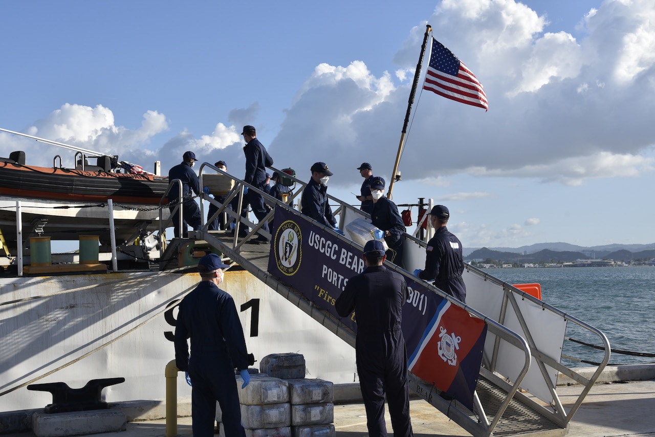 Service members bring seized drugs off cutter.