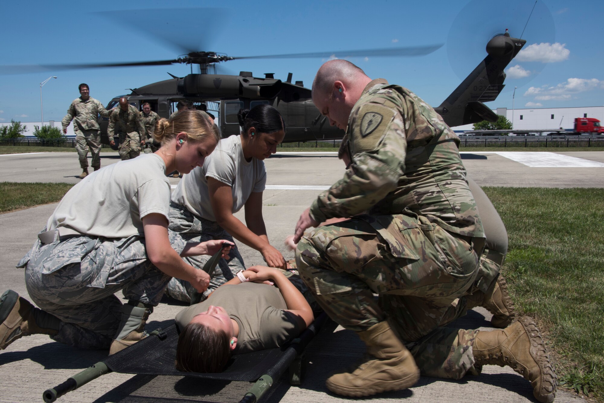 Airmen and Soldiers from the Indiana National Guard prepare to load a patient into a UH-60 Black Hawk helicopter during a medical transport exercise at the Johnson County Armory in Franklin July 2, 2020. Due to propeller wash, service members did not wear masks for safety reasons as the masks could cause debris interfering with helicopter propellers.