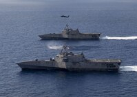 SOUTH CHINA SEA (Jan. 28, 2020) The Independence-variant littoral combat ships USS Gabrielle Giffords (LCS 10), bottom, and USS Montgomery (LCS 8) operate in the South China Sea, accompanied by an MH-60S Sea Hawk of Helicopter Sea Combat Squadron (HSC) 23, Jan. 28, 2020. Montgomery and Gabrielle Giffords are on rotational deployments to USINDOPACOM, conducting operations, exercises and port visits throughout the region and working hull-to-hull with allied and partner navies to provide maritime security and stability, key pillars of a free and open Indo-Pacific.