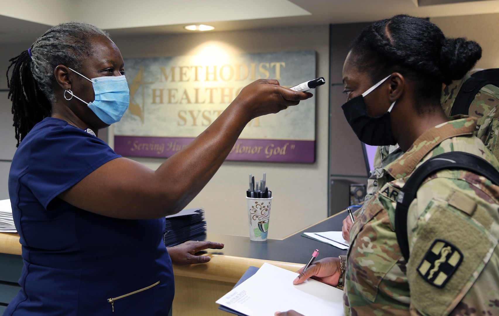 Sheryl Rudolph, registered nurse and Director of Education at Methodist Hospital San Antonio, takes the temperature of U.S. Army Capt. Terry Villas