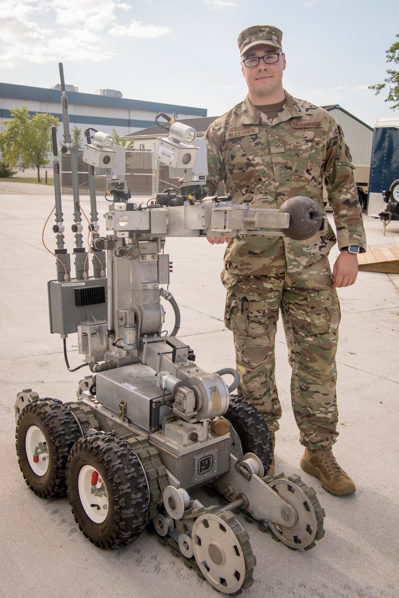 Senior Airman Stephan Wojciechowski, 434th Civil Engineer Squadron explosives ordnance disposal technician, poses with an Air Force medium sized robot holding a civil war era cannon ball at Grissom Air Reserve Base, Indiana, July 12, 2020. Wojciechowski and a team of four other EOD specialists were sent to the Berrien Springs County Plaza Museum Berrien Springs, Michigan, June 18, when a new employee discovered multiple munitions, one with the message ‘danger, might be active’ attached to a post-it note.  (U.S. Air Force photo/Master Sgt. Ben Mota)