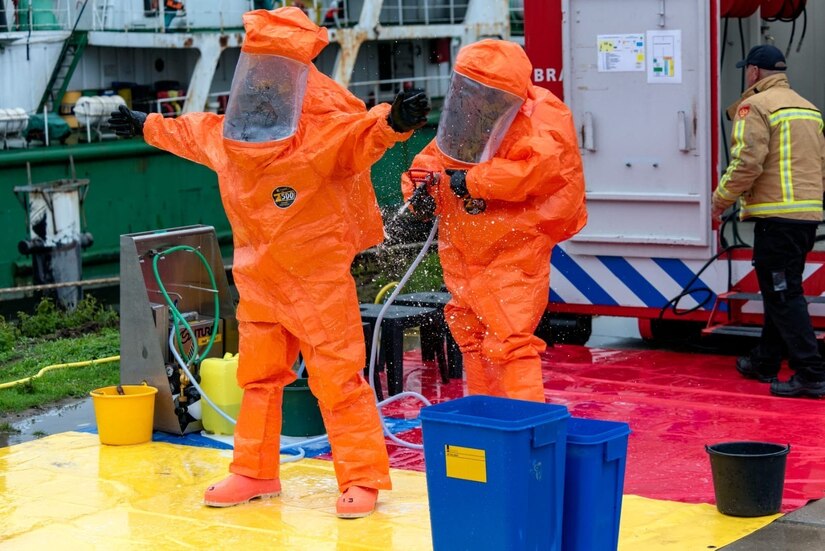 U.S Army Reserve Staff Sgt. William Haynes, survey team member with the 773rd Civil Support Team, 7th Mission Support Command, right, decontaminates fellow team member Sgt. Jonathan Medina with the Dutch Fire Department's decontamination system during a training exercise in Gravendeel, Netherlands, July 8, 2020. The one-day CBRN situational training exercise focused on a CBRN incident on a maritime vessel at the Dutch Harbor in Gravendeel, Netherlands.  (Photo by Netherlands Captain Tom Martens)