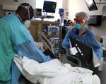 Army Capt. Stacey Johnson, critical care nurse from Urban Augmentation Medical Task Force-627, provides positioning aids to a COVID-19 patient