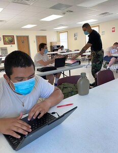 Team leader Heriberto Ruiz speaks with Wisconsin Challenge Academy cadet Dominick Bennett as fellow cadet Luis Castro works to complete core requirements June 5, 2020, at Fort McCoy, Wis. The COVID-19 pandemic required the academy to send its cadets home during the five-and-a-half month residential phase of the program.