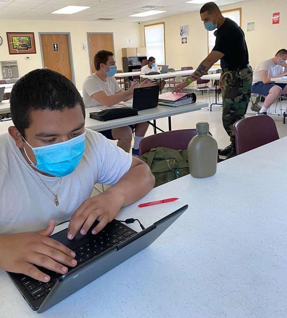 Team leader Heriberto Ruiz speaks with Wisconsin Challenge Academy cadet Dominick Bennett as fellow cadet Luis Castro works to complete core requirements June 5, 2020, at Fort McCoy, Wis. The cadets had to return home during the residential phase of the program due to the COVID-19 pandemic.