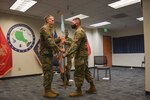 A man hands another man a flag during a ceremony