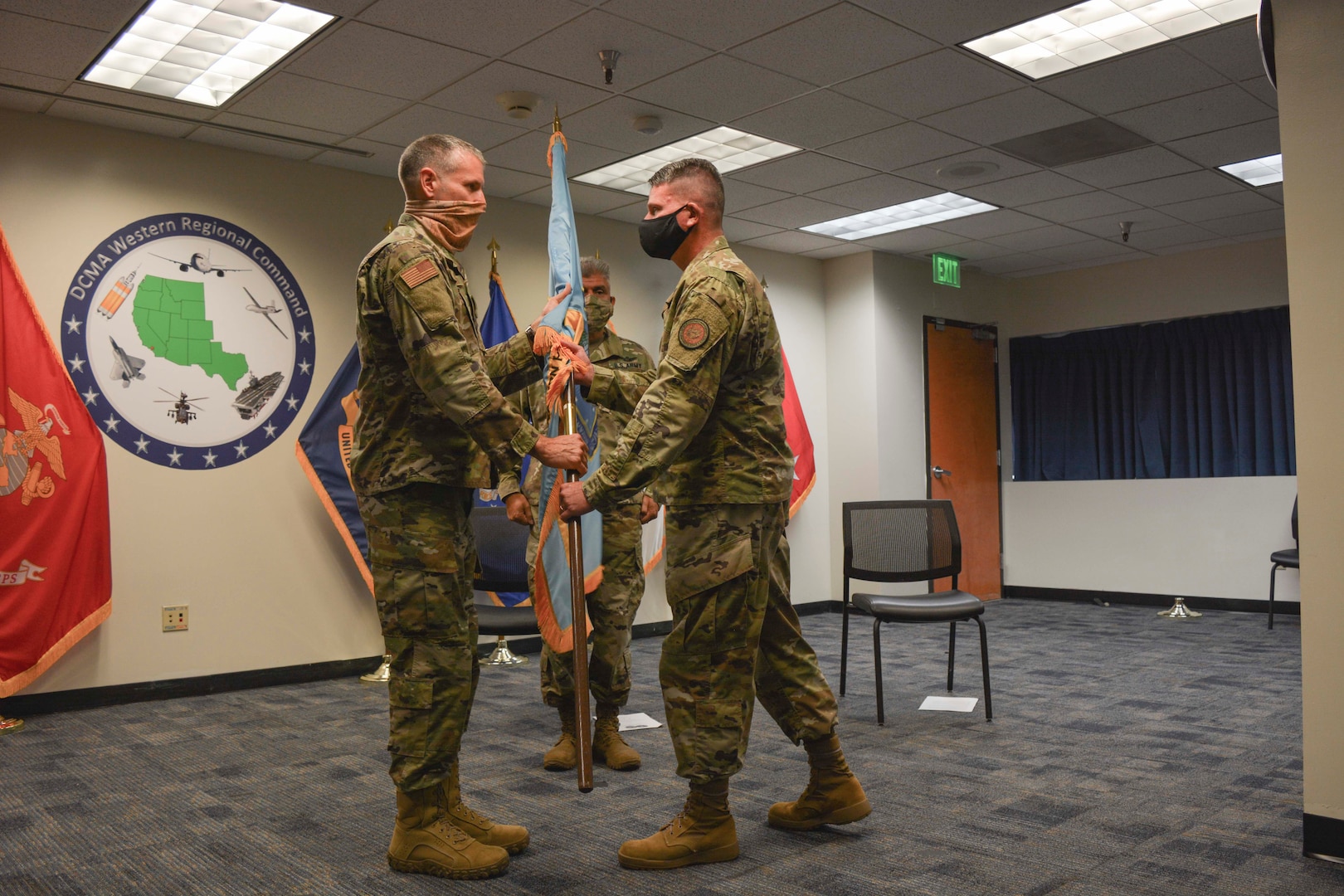 A man hands another man a flag during a ceremony