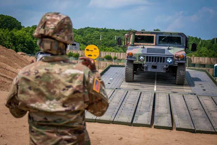 A soldier guides a Humvee across a bridge.