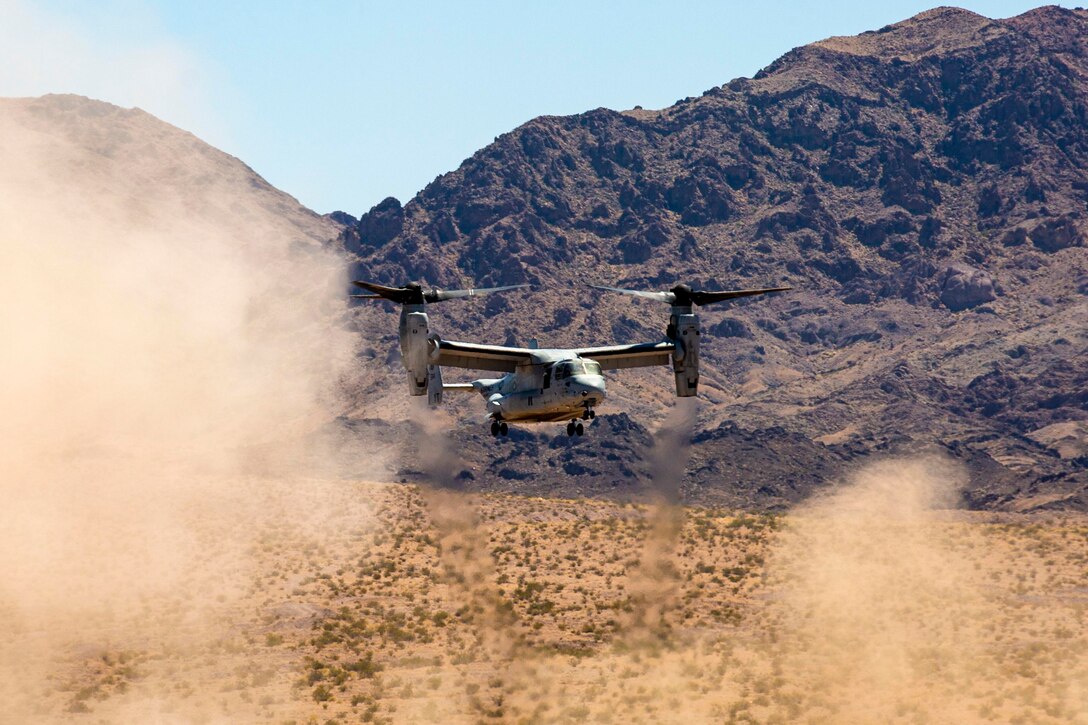 A helicopter prepares to land in a desert.