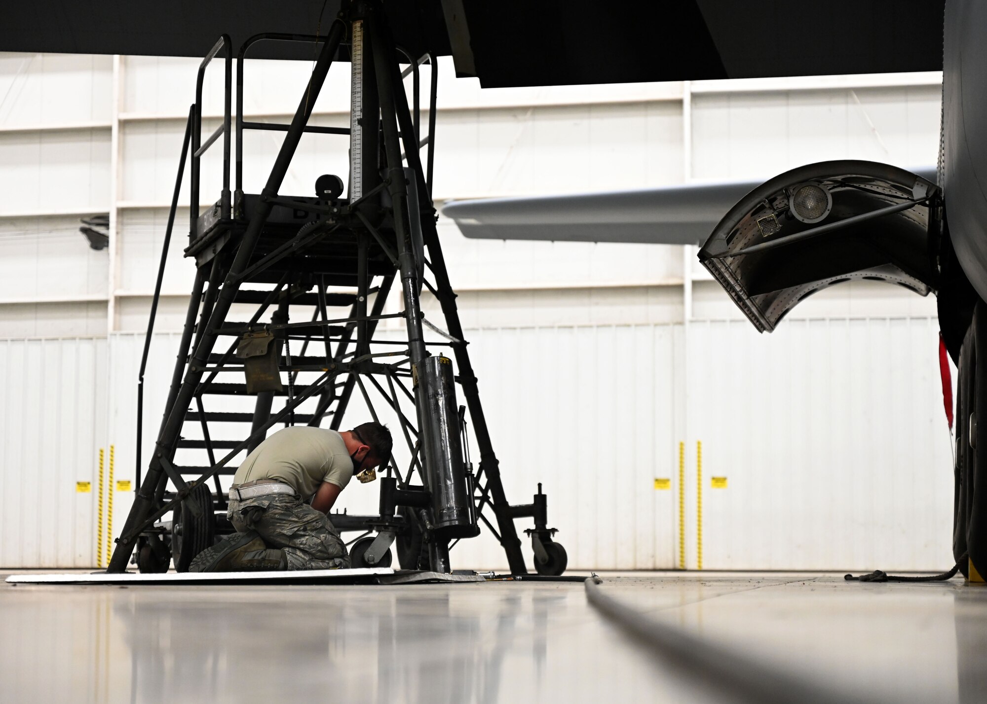 An Airman connects a hose to a hydraulic pump.