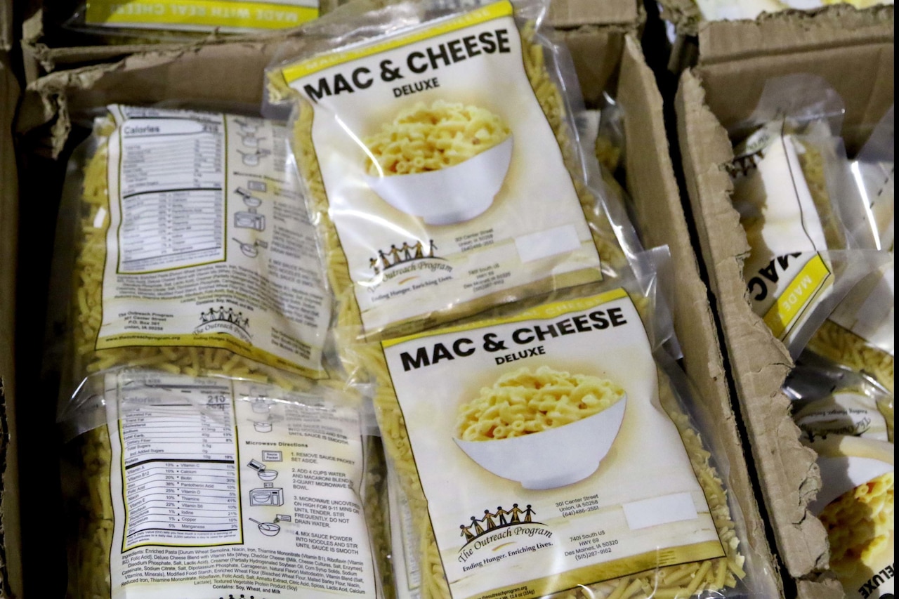 Plastic bags of macaroni and cheese fill a cardboard box in preparation for distribution.