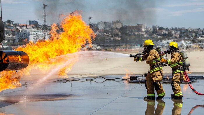 U.S. Marines work with firefighters from around San Diego County to put out a fire on a mobile aircraft firefighting trainer during a training evolution at the San Diego International Airport in San Diego, July 10.