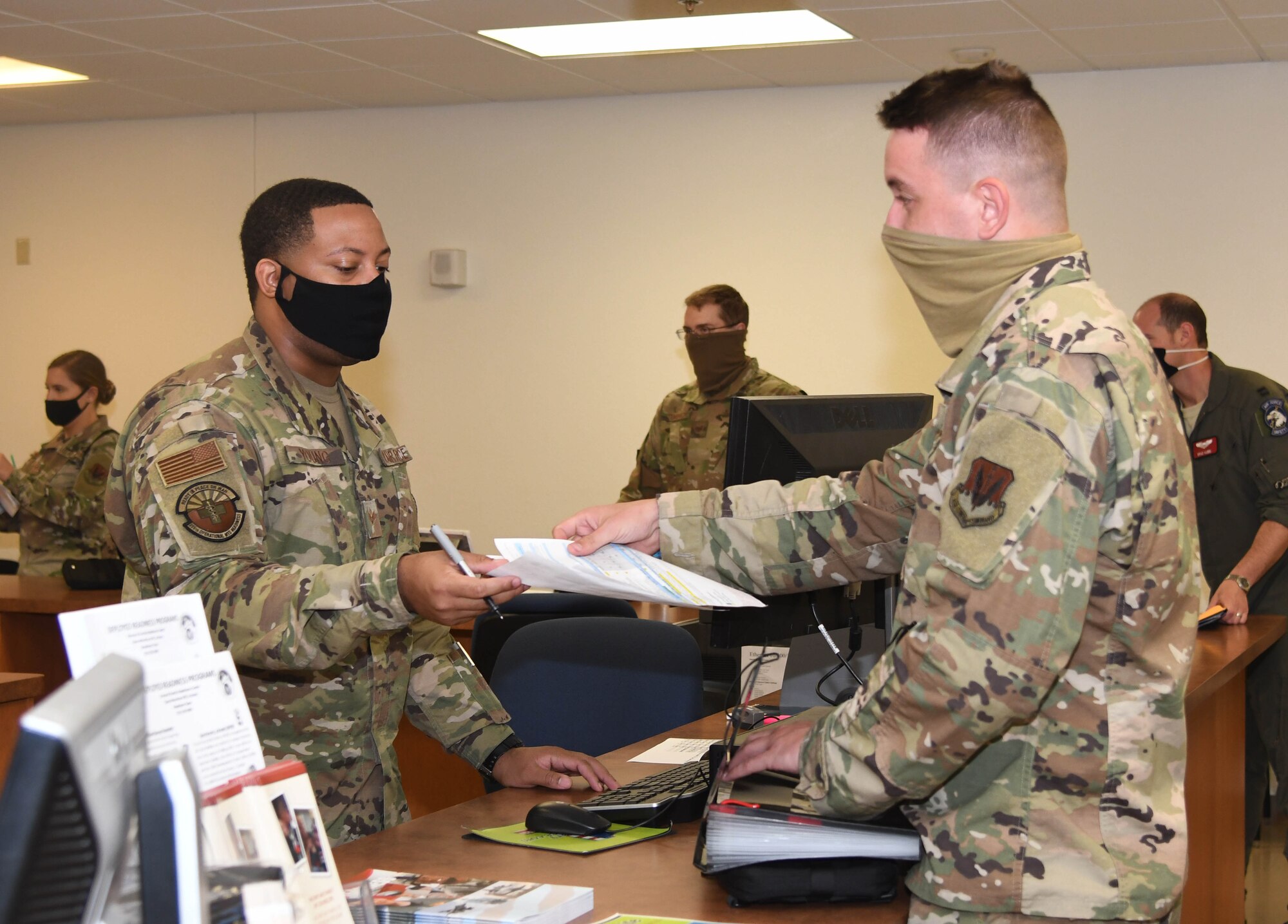 A photo of an Airman handing a piece of paper.
