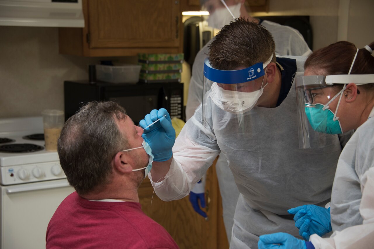 A guardsman administers a COVID-19 nasal swab test as a nurse watches.