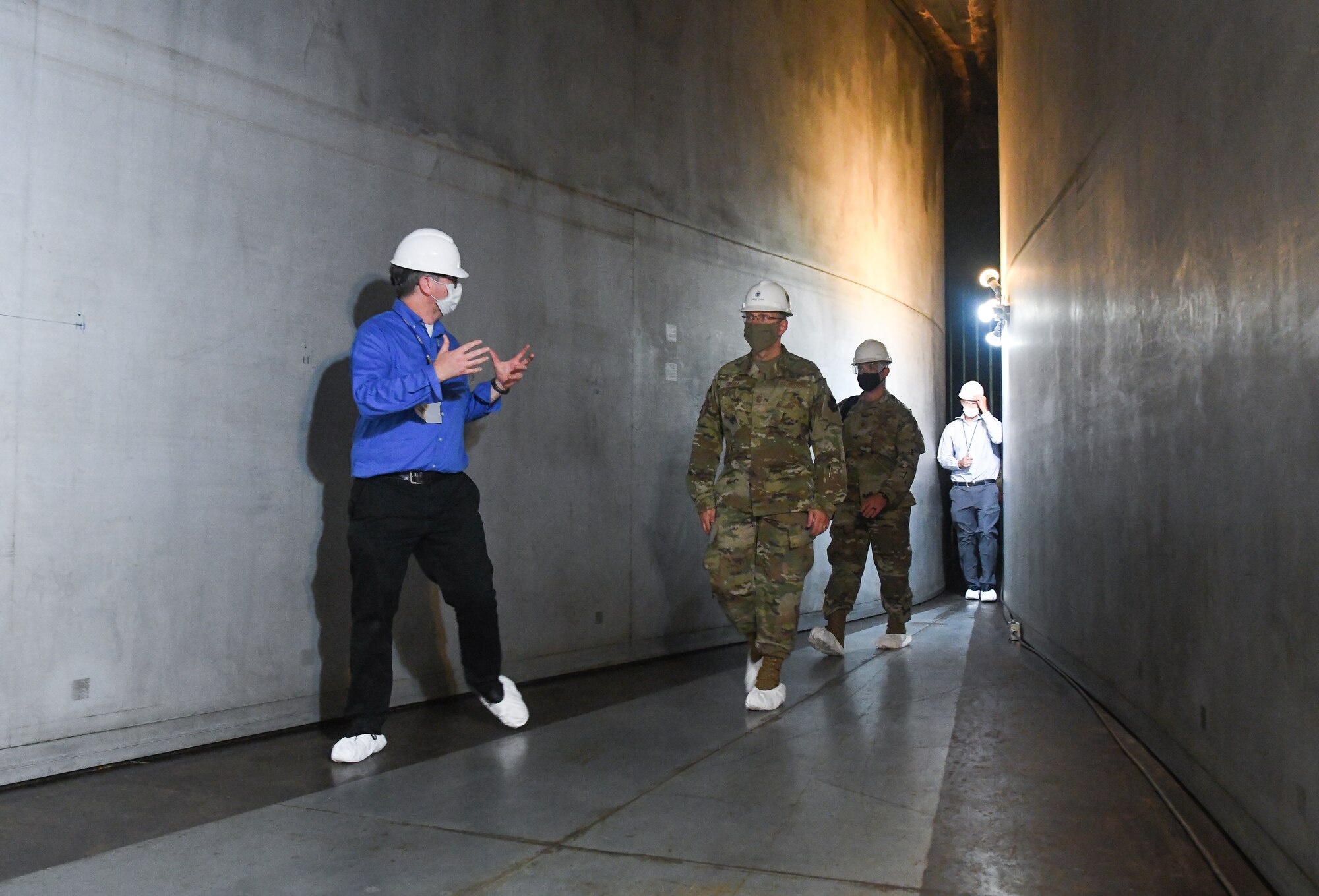 Scott Meredith, left, technical advisor for Arnold Engineering Development Complex (AEDC) Flight Systems Branch, talks about the 16-foot supersonic wind tunnel as he, Chief Master Sgt. Stanley Cadell, second from left, command chief, Air Force Materiel Command, and others, walk through the flexible nozzle of the tunnel, July 8, 2020, at Arnold Air Force Base, Tenn., headquarters of AEDC. The visit to the Base by Cadell and Gen. Arnold W. Bunch Jr., commander, Air Force Materiel Command, focused on COVID-19 response and diversity and inclusion. (U.S. Air Force photo by Jill Pickett) (This image has been altered by obscuring a badge for security purposes.)