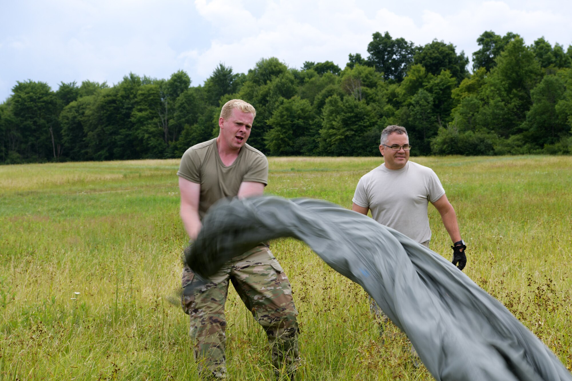 Senior Airman Chuck Kunc and Tech. Sgt. Zachary Ford, air transportation specialists, both with the 76th Aerial Port Squadron, wrap up a parachute during a training exercise, Camp Garfield, July 12, 2020. The training exercise provided cargo drop experience for the 757th Airlift Squadron.