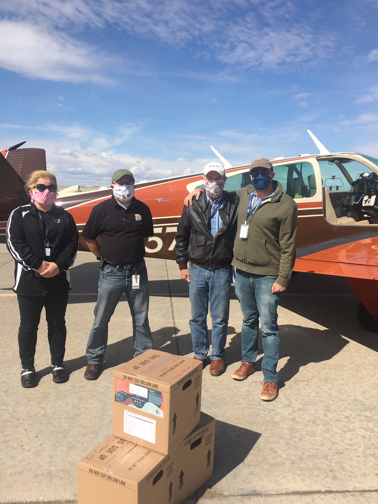 Four men with supplies in front of an airplane