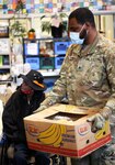 Sgt. Nikko Ethridge, a cavalry scout with 1st Battalion, 161st Infantry Regiment, helps a visitor at St. Leo's Food Bank in Tacoma. The Guard has helped process, pack and distribute more than 35 million pounds of food.