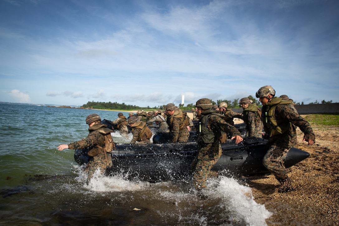 A group of Marines carry a rubber craft into the water.