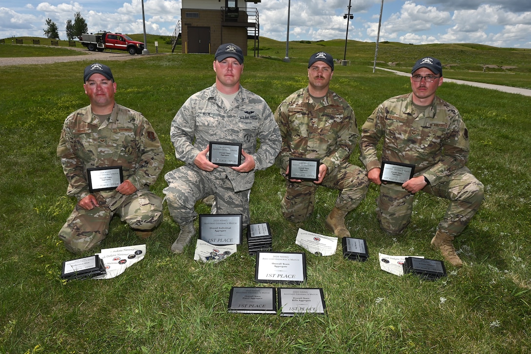 Four Airmen kneel for a photo with awards they earned at the 2020 North Dakota National Guard Adjutant General’s Combat Marksmanship Match at the Camp Grafton Training Center firing complex, near McHenry, North Dakota, July 12, 2020.