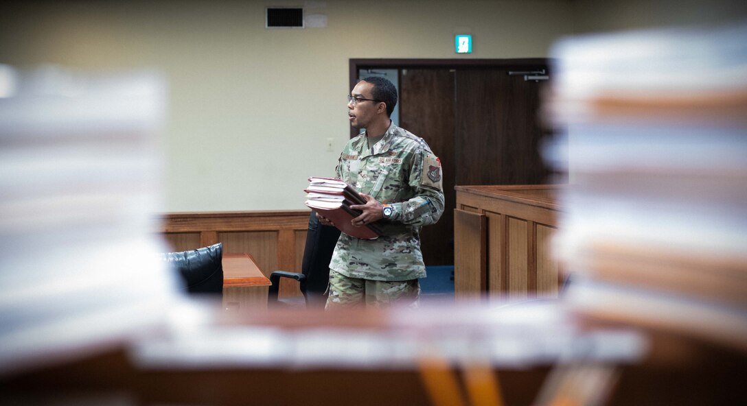 Senior Airman Dorien A. Hamilton, 18th Wing Judge Advocate military justice paralegal walks a stack of documents into the court room at Kadena Air Base.