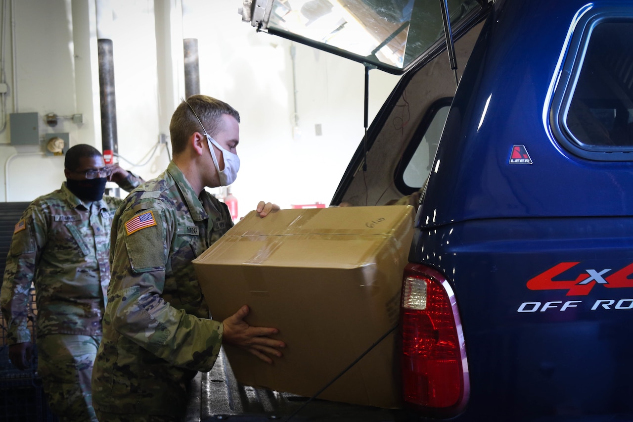 National Guardsmen load boxes of food into a vehicle.