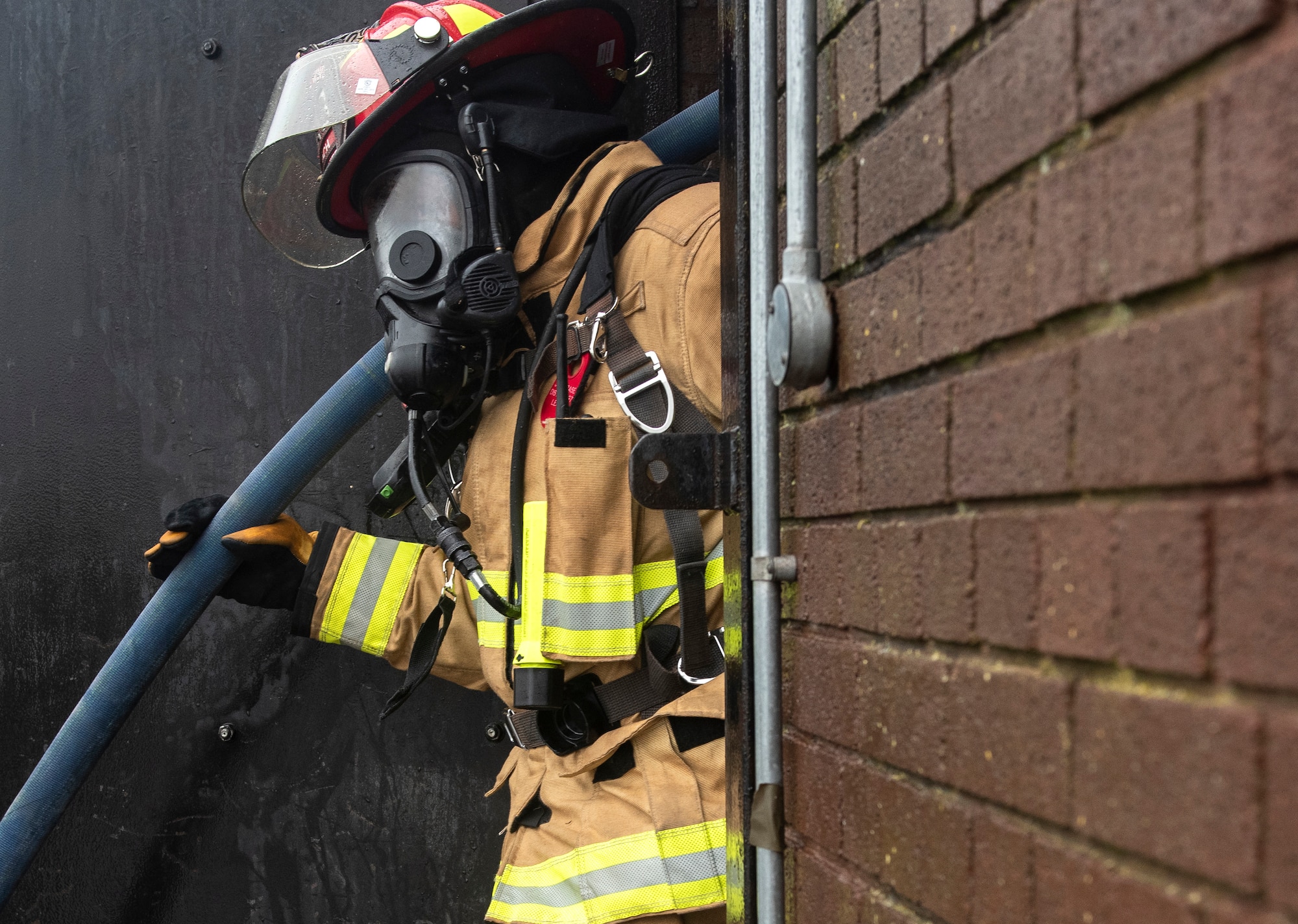 A U.S. Air Force firefighter assigned to the 48th Civil Engineering Squadron exits a structural training facility after completing a controlled burn training exercise at Royal Air Force Lakenheath, England, July 8, 2020. Liberty Wing firefighters participate in live fire and smoke training quarterly to ensure readiness for real-world situations. (U.S. Air Force photo by Airman 1st Class Jessi Monte)