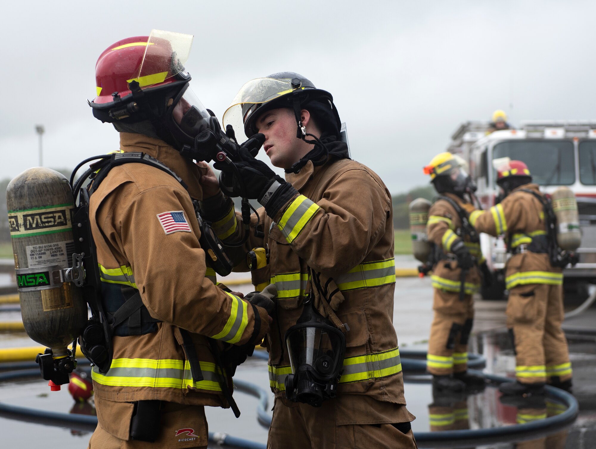 U.S. Air Force firefighters assigned to the 48th Civil Engineering Squadron perform buddy checks on their personal protective equipment prior to a controlled burn training exercise at Royal Air Force Lakenheath, England, July 8, 2020. Structural training exercises allow Liberty Wing firefighters to improve communication and teamwork in low visibility, high stress environments. (U.S. Air Force photo by Airman 1st Class Jessi Monte)