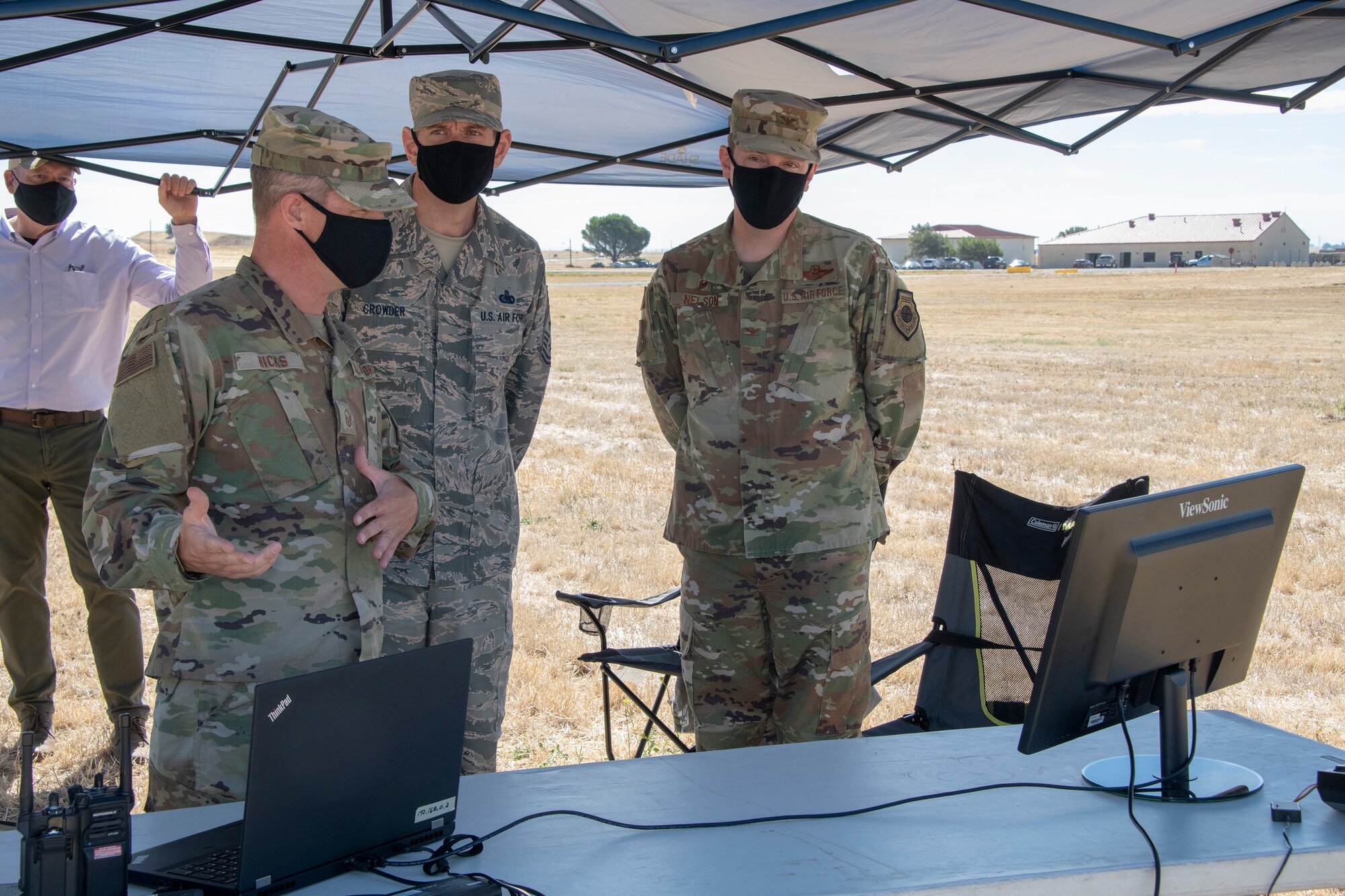U.S. Air Force Master Sgt. Joshua Hicks, left, 60th Security Forces Squadron flight chief, briefs Col. Jeffrey Nelson, right, 60th Air Mobility Wing commander, and Chief Master Sgt. Derek Crowder, 60th AMW command chief on the Easy Aerial drone system during Leadership Rounds July 10, 2020, at Travis Air Force Base, California. The mobile and fully autonomous drone-based monitoring system enhances 60th SFS incident management and physical security of the base. The Leadership Rounds program provides 60th AMW leadership an opportunity to interact with Airmen and get a detailed view of each mission performed at Travis AFB. (U.S. Air Force photo by Heide Couch)