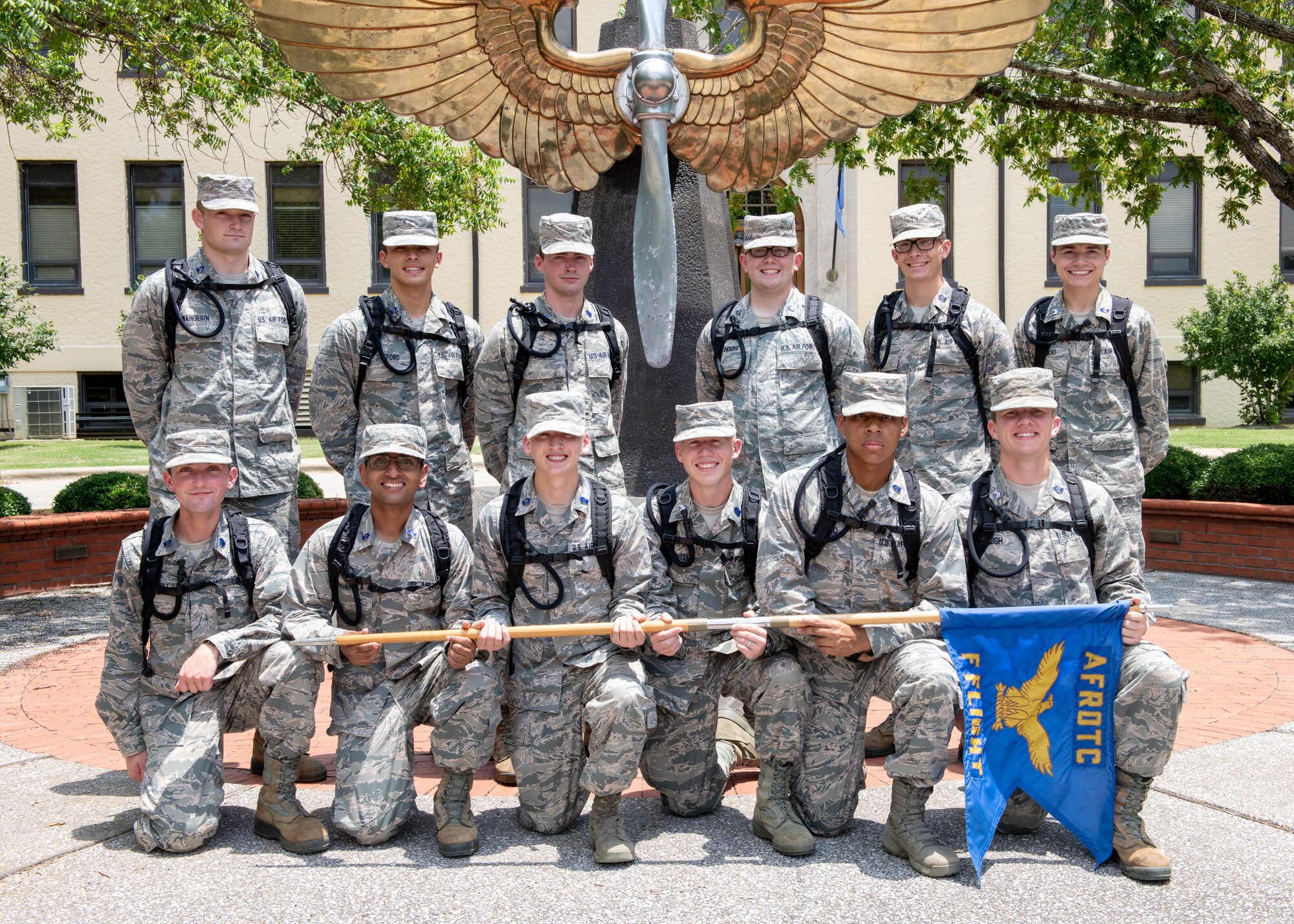 Air Force Reserve Officer Training Corps flight poses for a photo in front of the prop and wings statue outside of the Air University Headquarters building