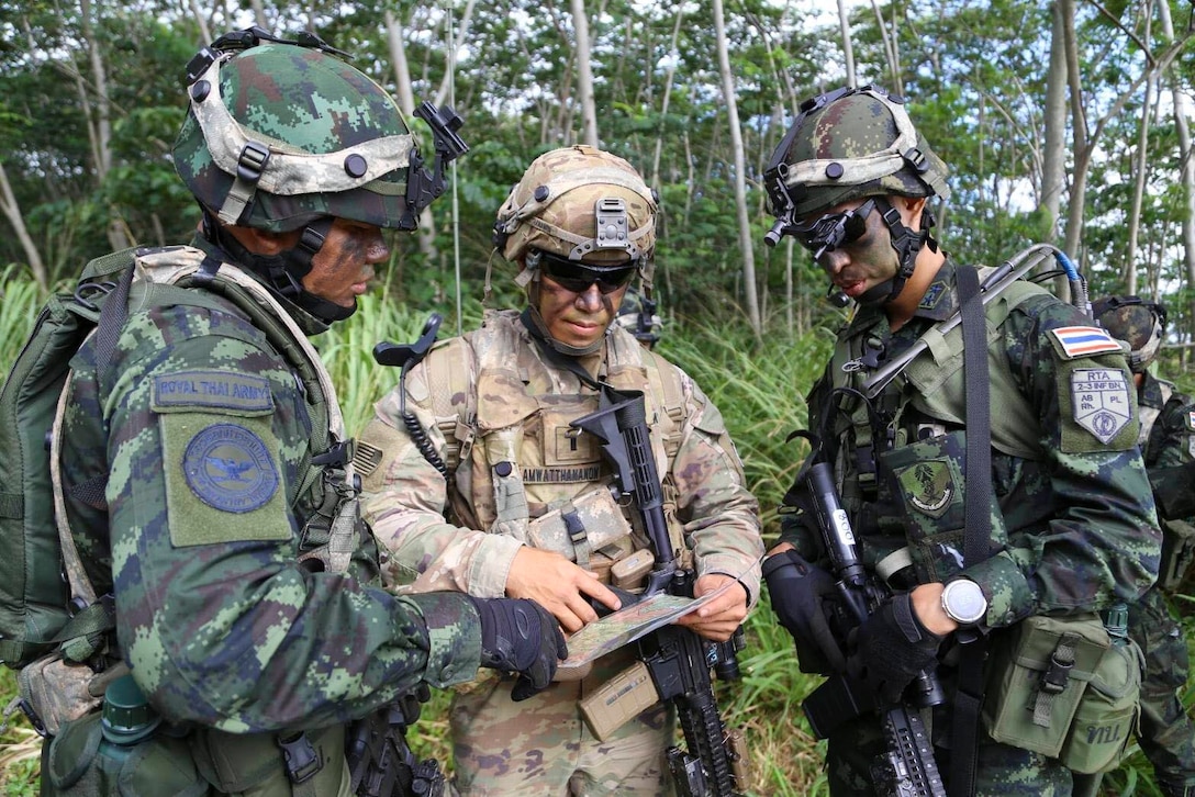 Three soldiers stand together looking at a map.