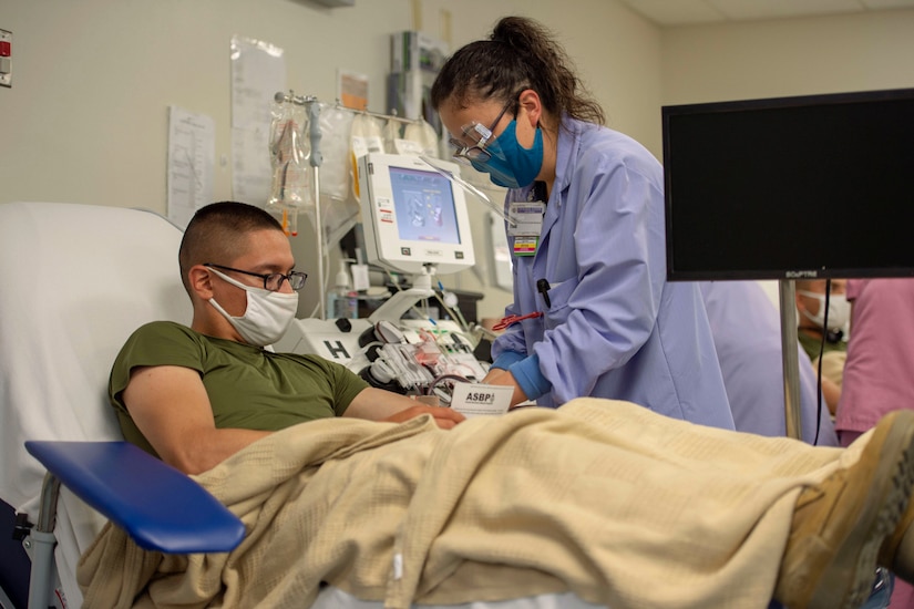 A Marine gets blood drawn while lying in a hospital bed.