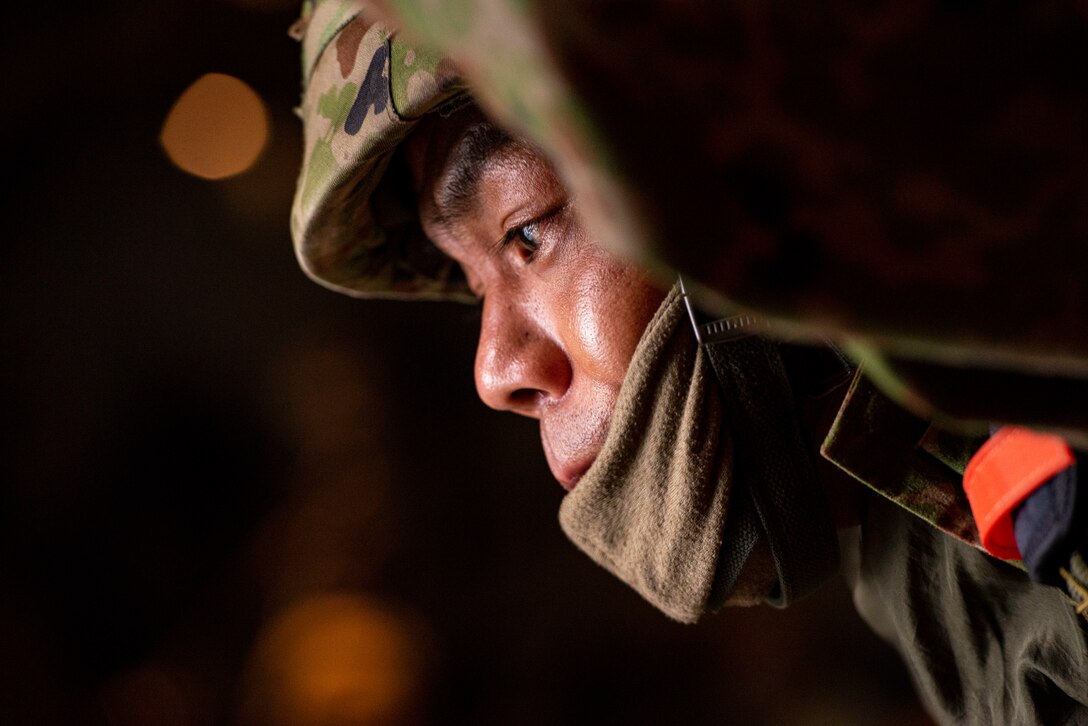 A Japan Ground Self Defense Forces jumpmaster looks out a side door of a C-130J Super Hercules