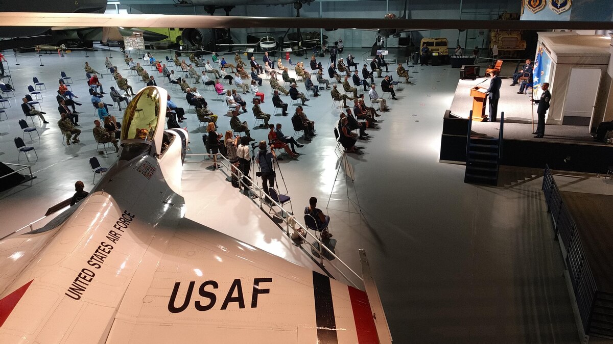 Photo shows people sitting spaced apart while looking at a stage.