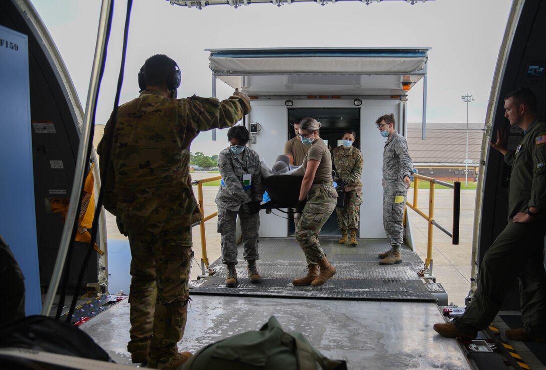 Maj. Reynel Garcia, chief of aeromedical operations and training assigned to Air Mobility Command Headquarters at Scott Air Force Base, Illinois, directs Airmen carrying a non-ambulatory patient into a KC-46A Pegasus July 10, 2020, at Joint Base Andrews, Maryland. Of the five patients transited, three patients were ambulatory and two required transport via litters. (U.S. Air Force photo by Airman 1st Class Nilsa Garcia)