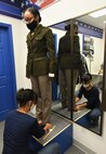 female in a uniform being measured by a tailor.
