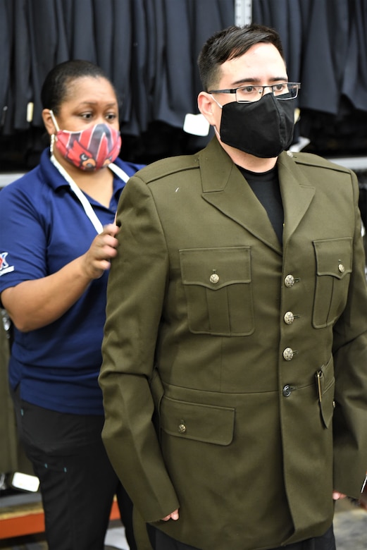 male Soldier being measured by a tailor being fitted for a uniform.