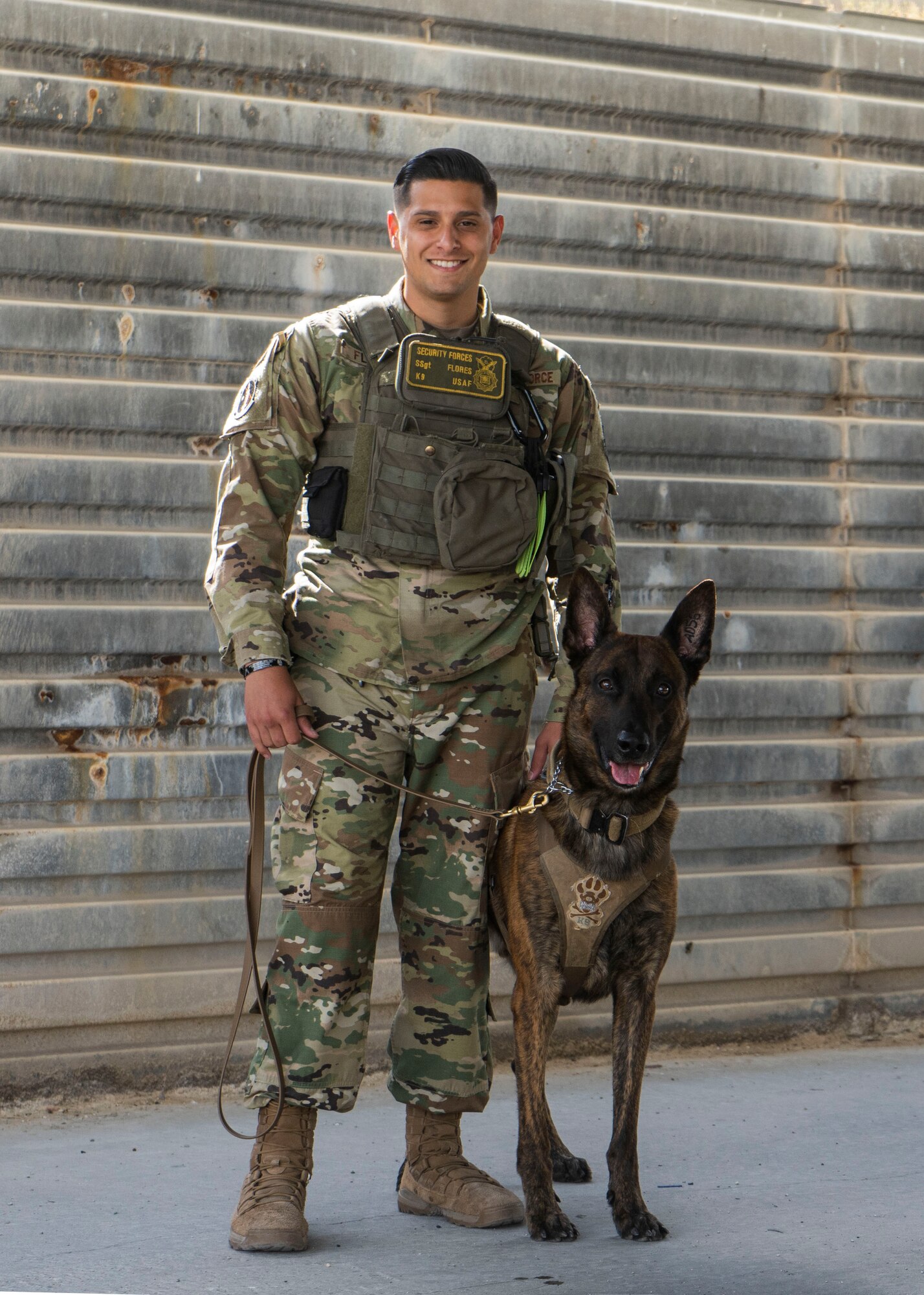 U.S. Air Force Staff Sgt. Angel Flores, 379th Expeditionary Security Forces Squadron military working dog handler, and AAslan, 379th ESFS MWD, pose together at Al Udeid Air Base, Qatar, July 2, 2020. MWDs train at Joint Base San Antonio-Lackland before being transferred to handlers. (U.S. Air Force photo by Senior Airman Olivia Grooms)