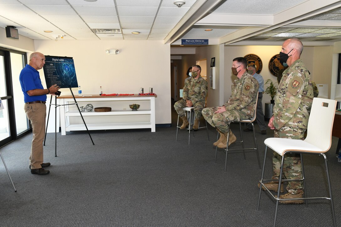 Photo shows people sitting in chairs listening to a briefing.