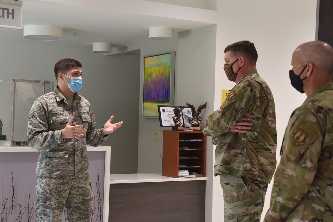 Photo shows an Airman speaking to the general and chief in front of the Public Health check in.
