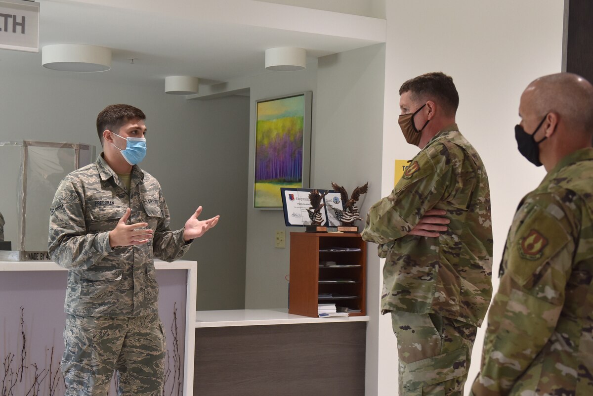 Photo shows an Airman speaking to the general and chief in front of the Public Health check in.