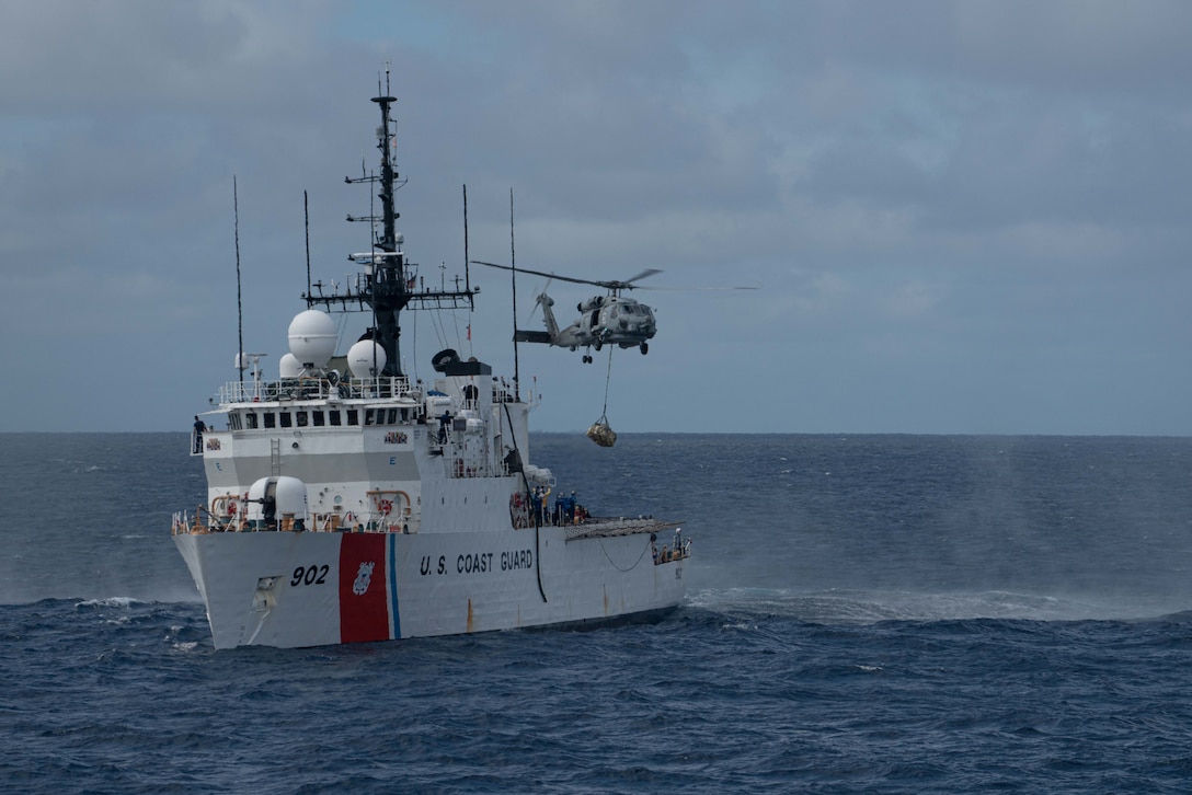 A navy helicopter transfer suspected contraband from a U.S. Coast Guard Cutter.