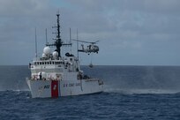 A navy helicopter transfer suspected contraband from a U.S. Coast Guard Cutter.