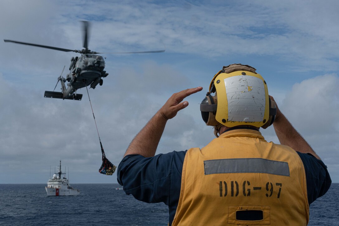 A U.S. Navy helicopter transfer suspected contraband from a U.S. Coast Guard Cutter.