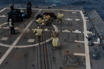 U.S. Sailors and Coast Guardsmen on USS Halsey  move suspected contraband on the flight deck.